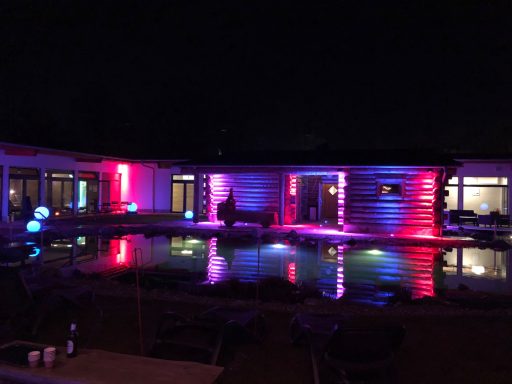 Beleuchtetes Schwimmbad mit bunten Lichtern bei Nacht.