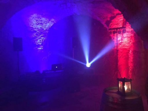 Dunkler Raum mit blauen und roten Lichtstrahlen, Lautsprechern und einer Laterne.