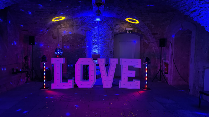 Große, beleuchtete Buchstaben „LOVE“ in einem stimmungsvoll beleuchteten Raum.