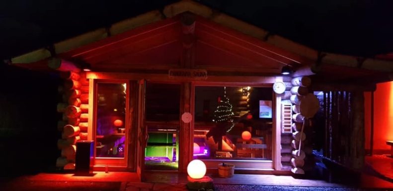 Buntbeleuchtete Holzhütte mit festlicher Dekoration und gemütlicher Atmosphäre.